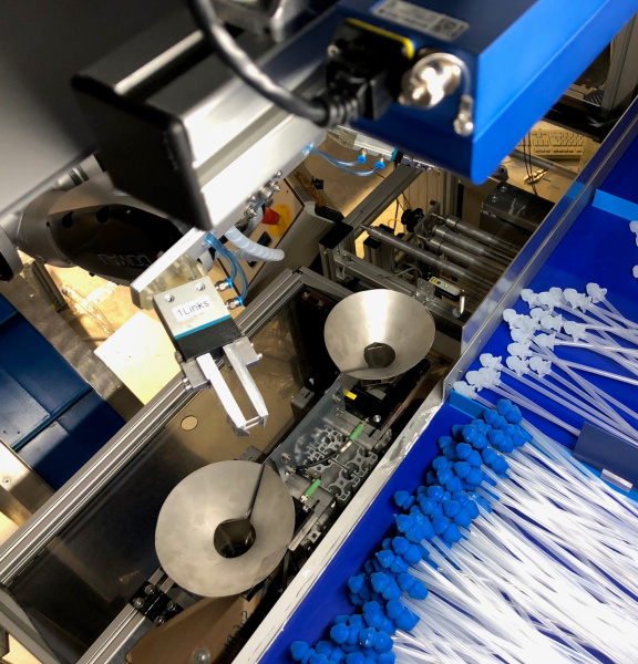 Un robot trie des cathéters avec des embouts bleus et blancs à l'aide d'une caméra 3D Ensenso.