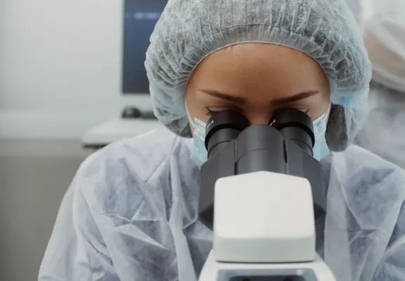 Une femme dans un laboratoire regarde dans un microscope.