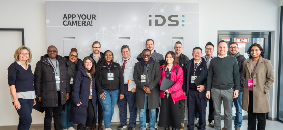 Une délégation de 14 membres du MIT REAP en visite chez IDS devant un mur de l'entreprise