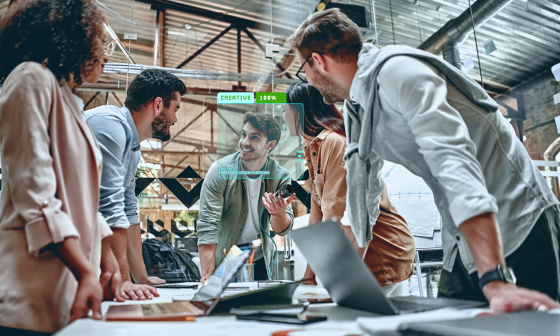 Collaboration : 5 personnes sont réunies autour d'un bureau avec des ordinateurs portables.