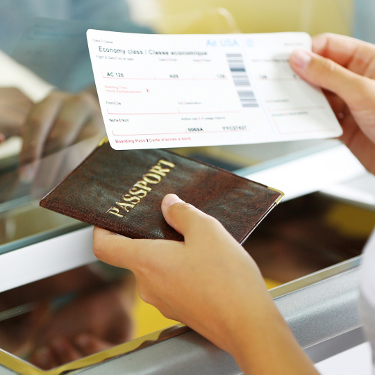 Une personne tient en main un billet d'avion et un passeport.