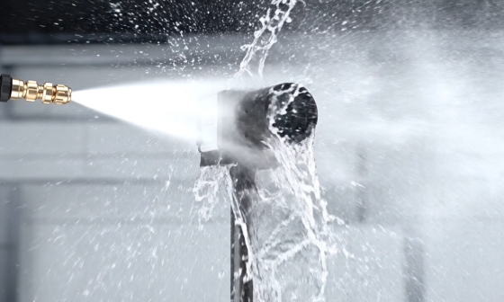 Une caméra industrielle est aspergée d'un puissant jet d'eau à courte distance.