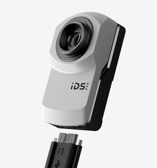 Caméra industrielle IDS uEye XC devant un fond gris.