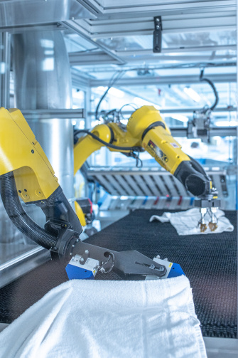 Deux robots déploient du linge dans une blanchisserie industrielle à l'aide de caméras IDS 2D et 3D.
