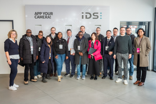 Groupe de visiteurs du programme MIT REAP lors de leur passage chez IDS, devant un mur.