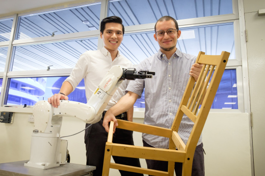 Deux scientifiques de la Nanyang Technological University avec une chaise et devant un robot