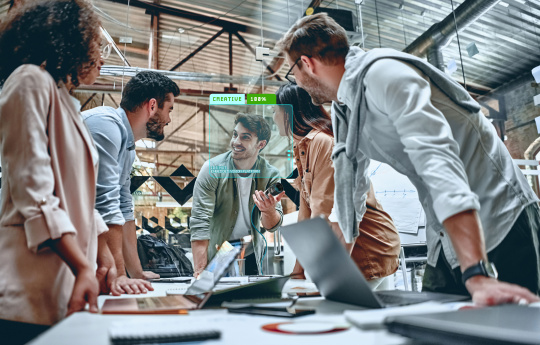 Collaboration : 5 personnes sont réunies autour d'un bureau avec des ordinateurs portables.