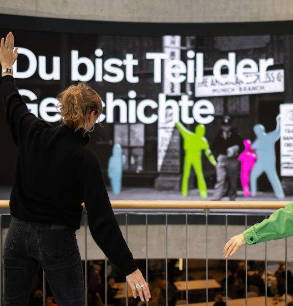 Deux personnes posent devant un grand écran interactif sur lequel apparaissent des silhouettes colorées