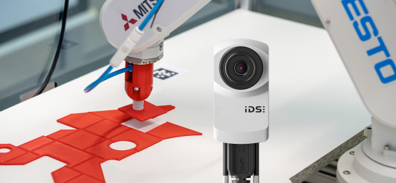 Le bras du robot place la pièce de puzzle rouge exactement au bon endroit, la caméra uEye XC au premier plan.