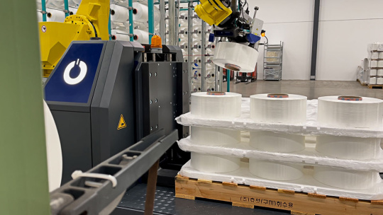 Le bras du robot trie des rouleaux de papier sur une palette