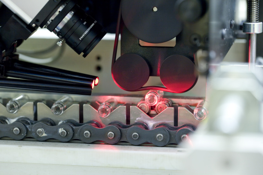 Une caméra surveille les ampoules produites, qui sont irradiées par une lumière rouge.
