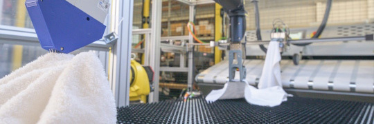 Bras robotisés jaunes avec serviettes dans une blanchisserie avec caméras IDS.